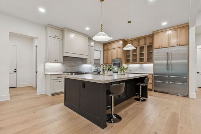 Kitchen with built in fridge, hanging light fixtures, light wood-style floors, a kitchen bar, and recessed lighting | Image 23