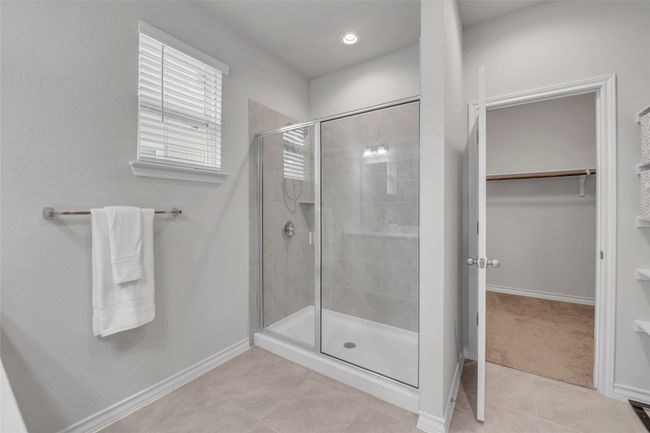 Full bath with tile patterned floors, a stall shower, a spacious closet, and baseboards | Image 11