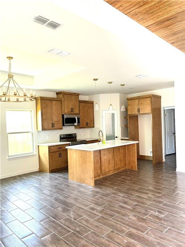 Kitchen with decorative light fixtures, visible vents, brown cabinetry, and stainless steel appliances | Image 15