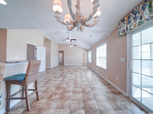 Unfurnished dining area with ceiling fan, vaulted ceiling, and a chandelier | Image 9