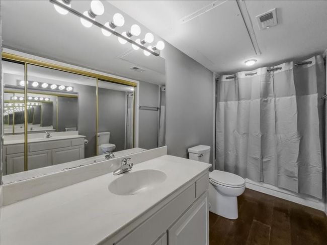 Bathroom featuring shower / tub combo with curtain, vanity, toilet, and hardwood / wood-style floors | Image 21