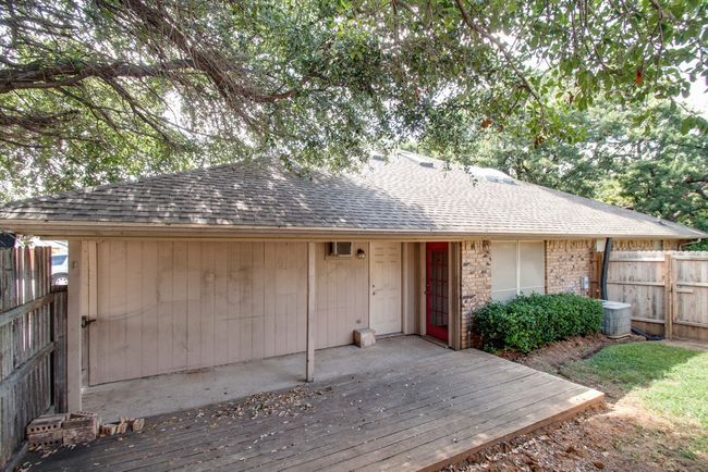Single story home featuring roof with shingles, a fenced backyard, a deck, and stone siding | Image 22