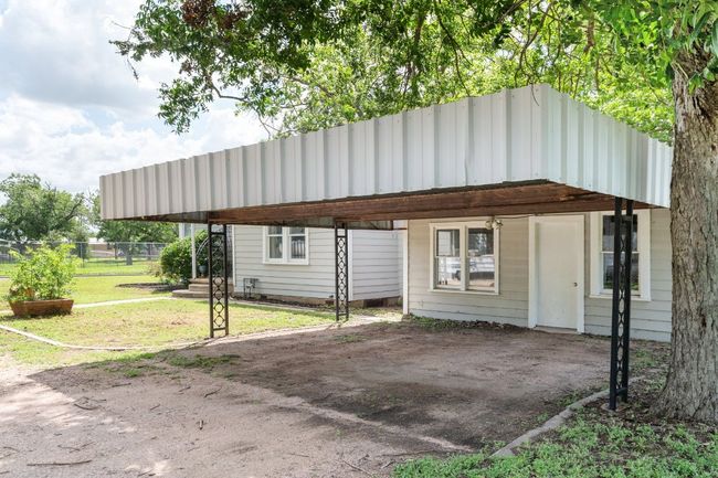 Original owner built a carport for two vehicles with beautiful wrought iron details. Door in carport leads to workshop area. | Image 30