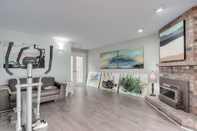Workout room with wood finished floors, a brick fireplace, and french doors | Image 11
