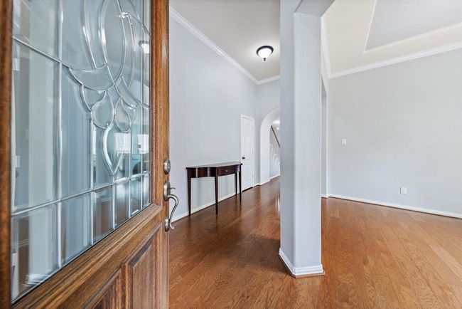 As you step through the front door, you're greeted by rich hardwood floors, neutral paint, and elegant crown molding, creating a warm and sophisticated first impression. | Image 4