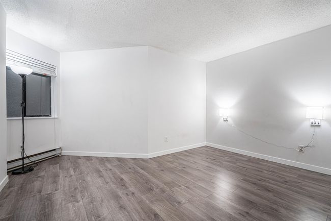 Unfurnished room featuring baseboards, a baseboard heating unit, wood finished floors, and a textured ceiling | Image 17