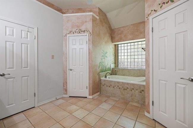Bathroom with tile patterned floors, a bath, vaulted ceiling, and baseboards | Image 25