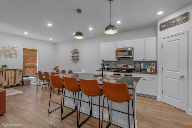 Kitchen with stainless steel appliances, a breakfast bar area, light wood-style floors, and a sink | Image 9