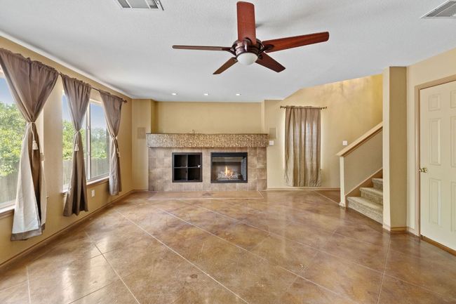 Unfurnished living room with a tile fireplace, stairs, and ceiling fan | Image 7