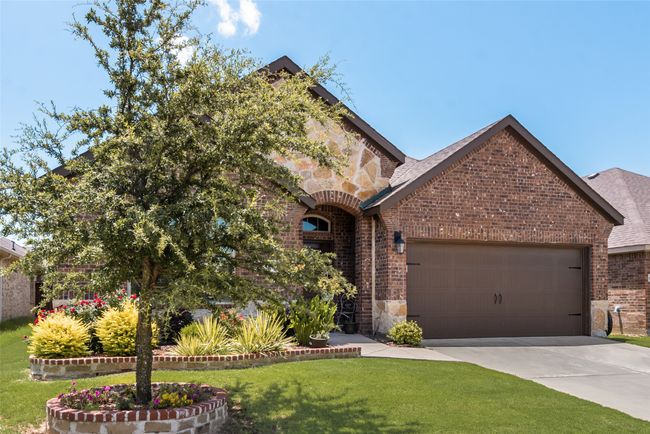View of front of home with brick siding, a garage, and stone siding | Image 37