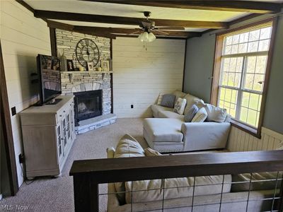 Living room featuring beamed ceiling, ceiling fan, carpet, and a stone fireplace | Image 3