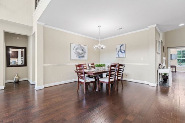 Dining area with dark wood-type flooring, a chandelier, crown molding, and baseboards | Image 13