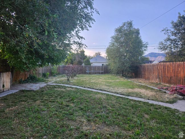 Fenced backyard featuring pathways to garden area and horseshoe pit | Image 22