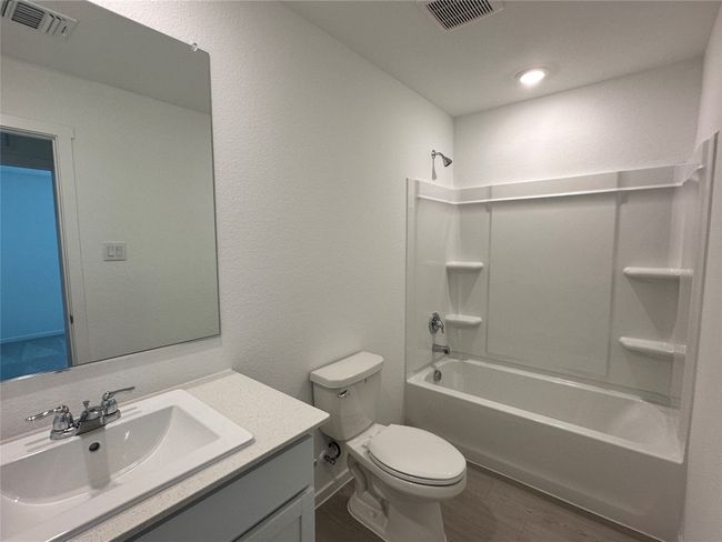 Bathroom with a textured wall, vanity, bathtub / shower combination, and wood finished floors | Image 15