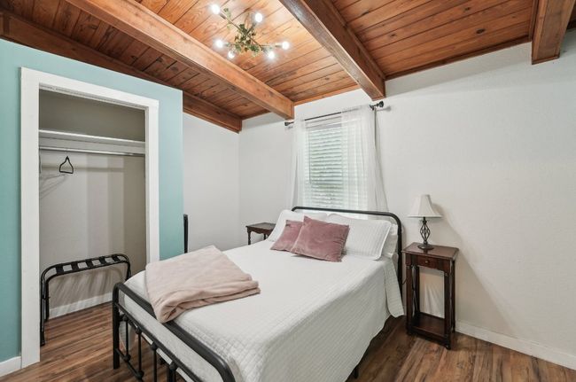 Bedroom with wood ceiling with exposed beams, baseboards, wood finished floors, and a closet | Image 19