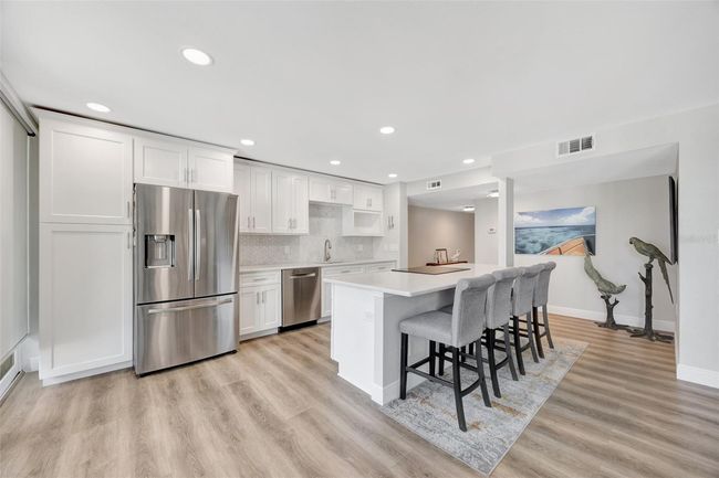 Enter into your open modern kitchen that with stainless appliances and room for 4 at the island. | Image 4