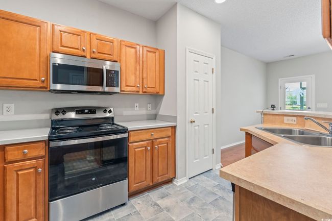 Kitchen featuring appliances with stainless steel finishes, a sink, light countertops, and baseboards | Image 10