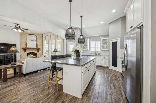 Kitchen featuring freestanding refrigerator, a kitchen breakfast bar, a fireplace, a center island, and dark wood finished floors | Image 6