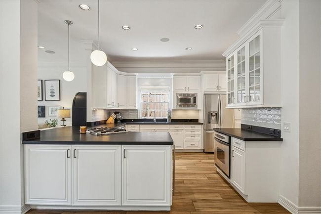 View of cooks kitchen from breakfast room. Leathered granite counters, gas range, electric oven and built-in microwave. | Image 9