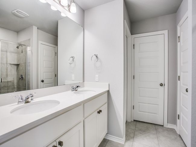 Bathroom with double vanity, a stall shower, baseboards, and tile patterned floors | Image 15