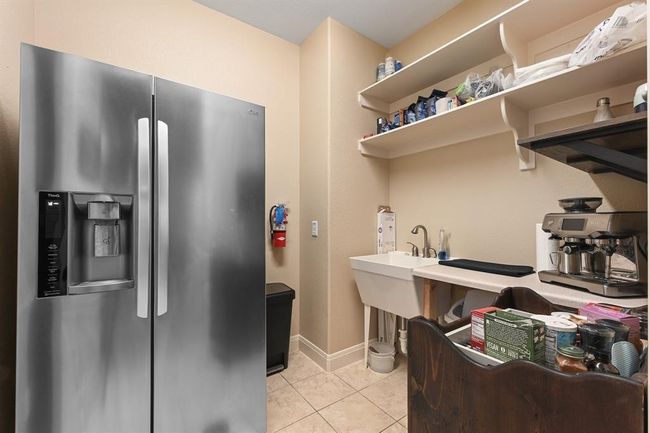 Kitchen featuring light tile patterned flooring, light countertops, open shelves, stainless steel fridge with ice dispenser, and baseboards | Image 12