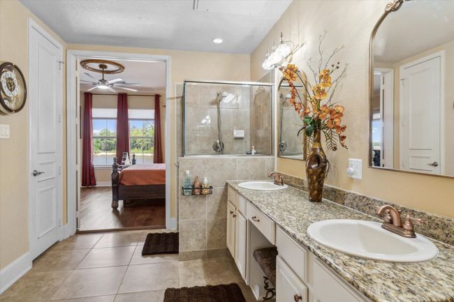 Bathroom featuring tiled shower, double vanity, ensuite bathroom, tile patterned flooring, and ceiling fan | Image 14