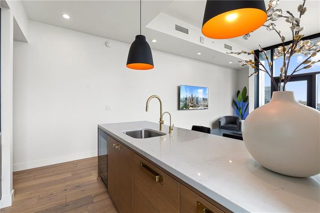 Kitchen with wood finished floors, baseboards, visible vents, a sink, and pendant lighting | Image 11