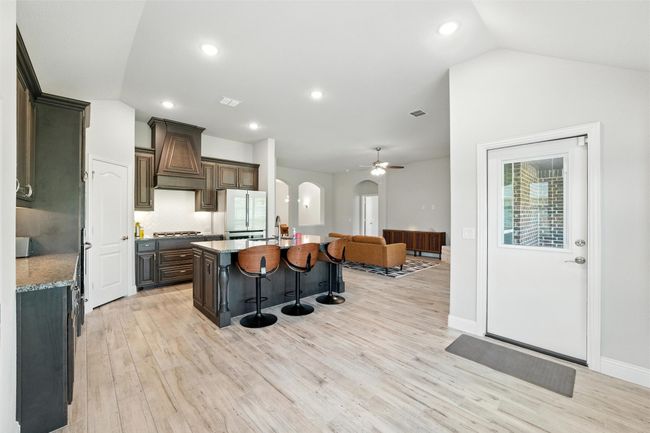 Kitchen featuring arched walkways, a kitchen bar, a ceiling fan, light wood-style flooring, and a kitchen island | Image 18