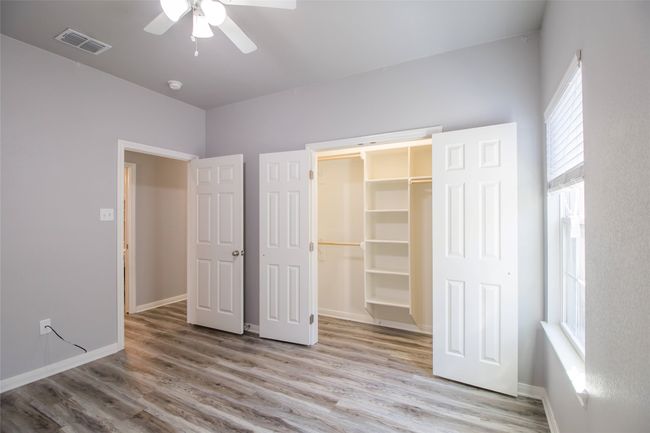 Unfurnished bedroom featuring wood finished floors, a walk in closet, and a ceiling fan | Image 10