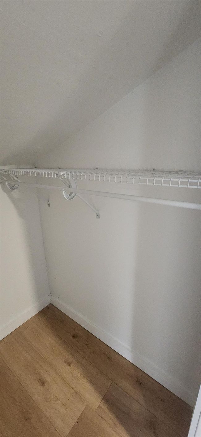 Spacious closet with light wood-style floors and lofted ceiling | Image 27