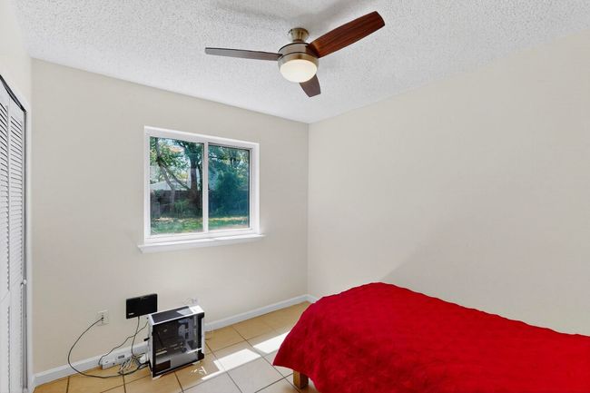 Bedroom with light tile patterned flooring, a textured ceiling, a ceiling fan, and a closet | Image 12