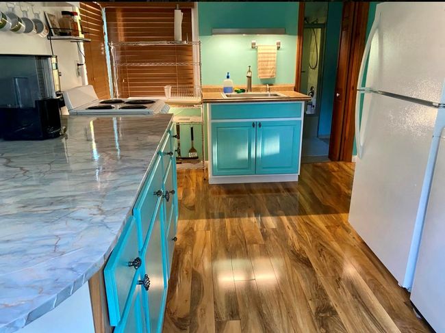Clothes washing area featuring a baseboard heating unit, dark wood-style flooring, cabinet space, washing machine and dryer, and baseboards | Image 10