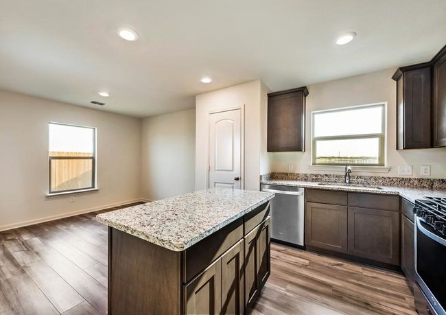 Kitchen featuring a sink, light wood-type flooring, dark brown cabinetry, and appliances with stainless steel finishes | Image 5