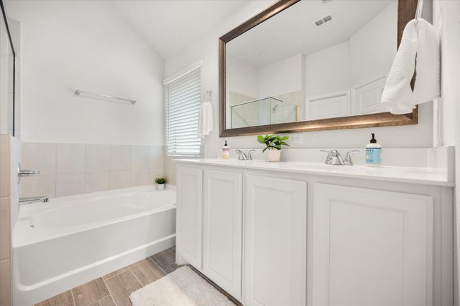 Full bathroom featuring a garden tub, double vanity, a shower stall, wood finished floors, and lofted ceiling | Image 16