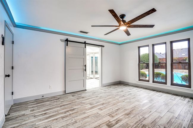 Unfurnished room with a barn door, ceiling fan, and light wood-style flooring | Image 18