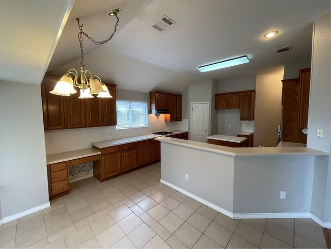 Kitchen featuring lofted ceiling, light countertops, stovetop, light tile patterned floors, and a peninsula | Image 8