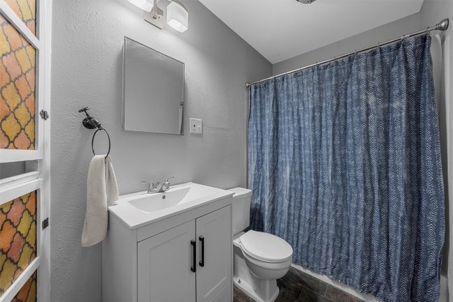 Full bathroom with vanity, curtained shower, and a textured wall | Image 16