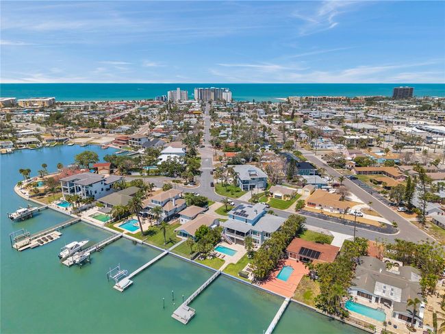 Aerial view showcasing the neighborhood of this luxury waterfront home, and the blue waters of the beach in the background. | Image 5