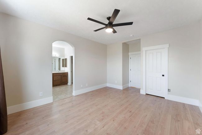 Primary bedroom with arched walkways, a ceiling fan, and light wood-style floors | Image 19
