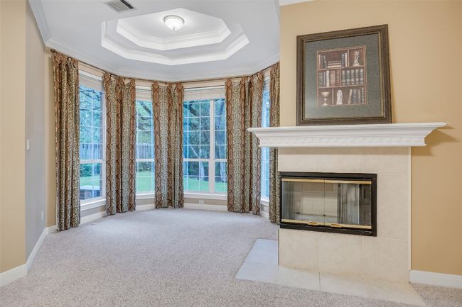 Unfurnished living room featuring ornamental molding, carpet, a tile fireplace, plenty of natural light, and a tray ceiling | Image 22