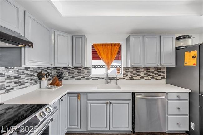 Kitchen with appliances with stainless steel finishes, a sink, gray cabinets, and tasteful backsplash | Image 7