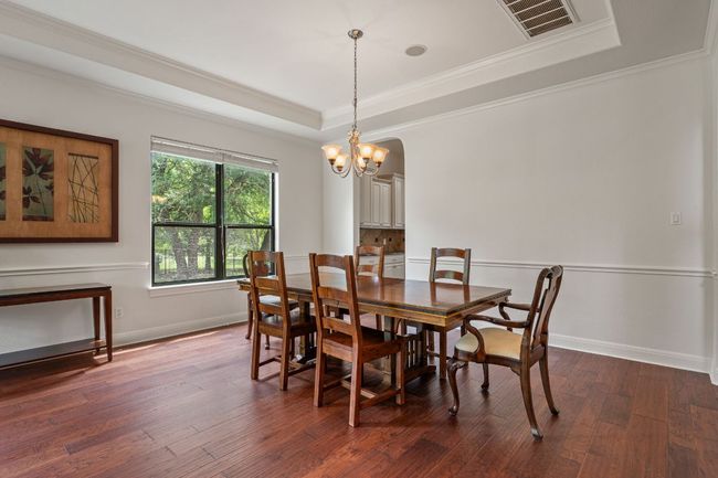 Dining room with crown molding, dark wood-type flooring, visible vents, and a tray ceiling | Image 16
