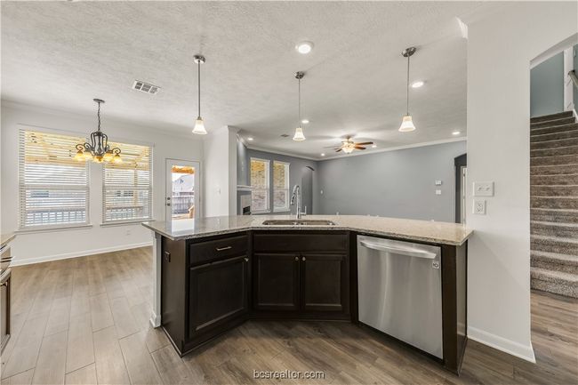 Kitchen featuring light stone counters, stainless steel dishwasher, ornamental molding, and sink | Image 9