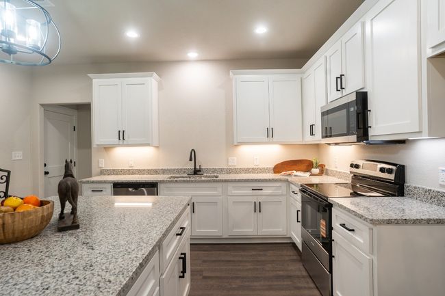 Kitchen featuring stainless steel appliances, a sink, white cabinets, dark wood-style floors, and recessed lighting | Image 10