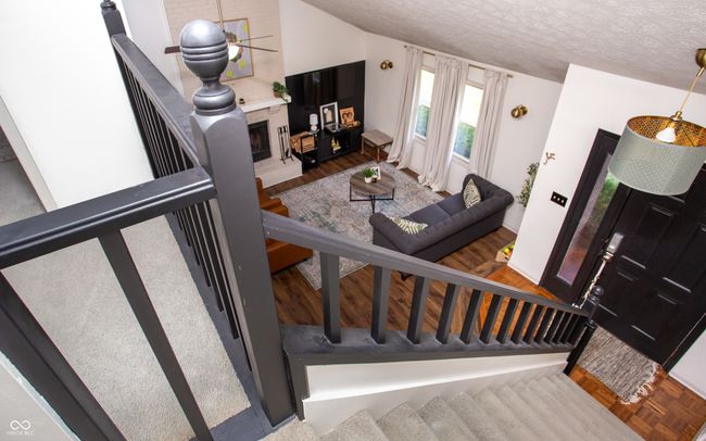 stairs with a textured ceiling, wood finished floors, and a fireplace | Image 29