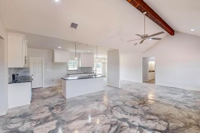 Kitchen with open floor plan, decorative backsplash, white cabinetry, and ceiling fan with notable chandelier | Image 8