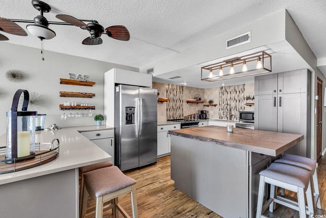 Kitchen with stainless steel appliances, visible vents, butcher block countertops, and open shelves | Image 17
