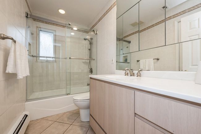 Bathroom featuring vanity, baseboard heating, tile patterned flooring, and tile walls | Image 14