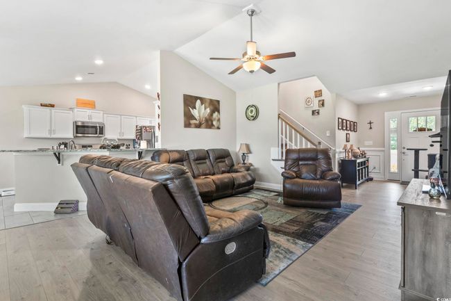 Living room featuring stairs, lofted ceiling, ceiling fan, light wood finished floors, and recessed lighting | Image 7