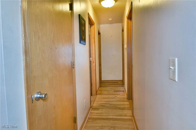 Corridor with light wood-style flooring and baseboards | Image 18
